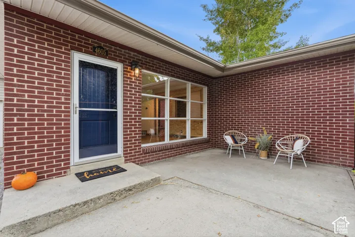 Brick exterior with a covered entry, concrete patio, and prominent front window