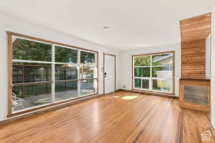 Hardwood flooring, expansive wall-to-wall windows, built-in display cabinetry, and a wood-paneled accent wall