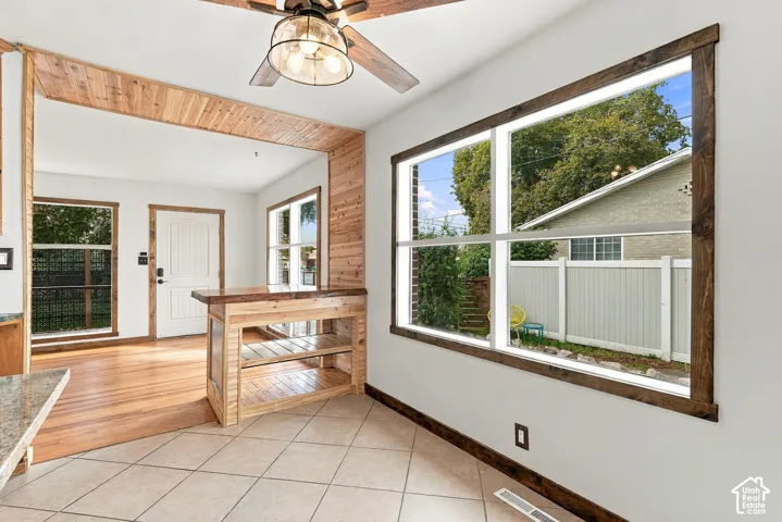 Tile flooring, wood-finish flooring, wood-clad doorway, built-in wood-finish island with shelving, and large windows with wood-finish trim