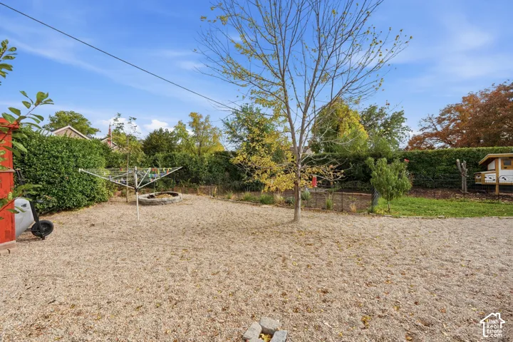Expansive gravel yard with mature trees and perimeter hedging