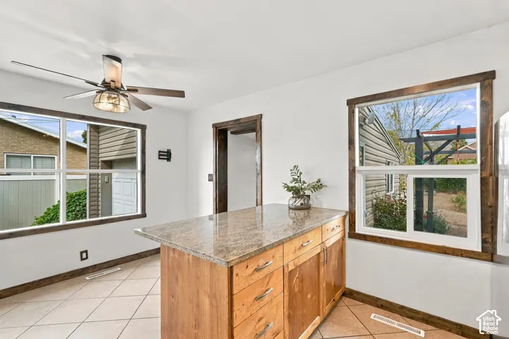 Kitchen island with a light-toned countertop, wood-finish cabinetry, and contemporary hardware