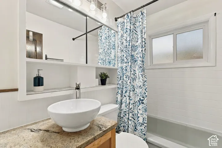 Recessed wall shelving, vessel sink, light-toned countertop, vanity lighting, and a window with frosted glass