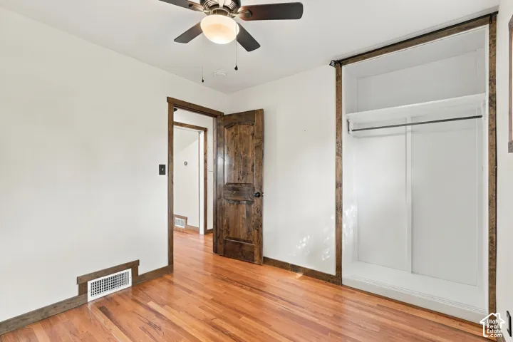 Hardwood flooring throughout, a ceiling fan with integrated lighting, and a built-in closet with sliding doors and an upper shelf