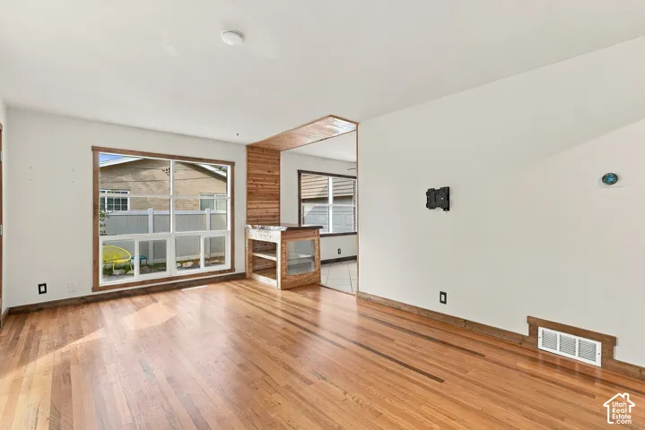 Wood-finish flooring throughout, large window with wood trim, wood accent wall, and built-in wood shelving unit