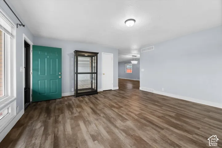 Interior area featuring wood-finish flooring, a solid-panel door with a bold teal finish, and neutral wall tones