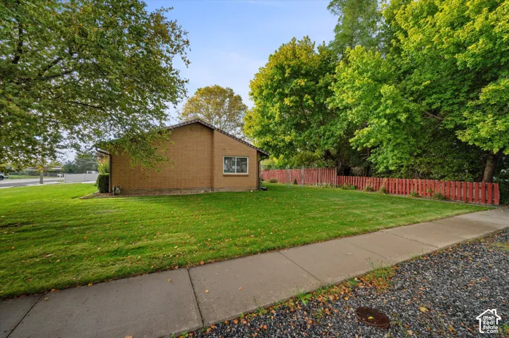 Brick exterior siding, expansive lawn, mature trees, and a wooden privacy fence