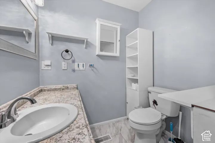 Bathroom featuring a countertop with an integrated oval sink, built-in tall shelving, a wall-mounted medicine cabinet, and stone-pattern flooring