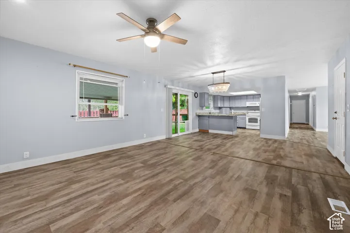 Open floor plan featuring wood-finish flooring, a ceiling fan, sliding glass door, and a kitchen equipped with cabinetry and a peninsula