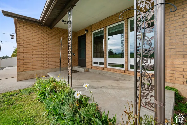 Brick exterior facade featuring a covered concrete porch, decorative metal pillars, and large multi-pane windows