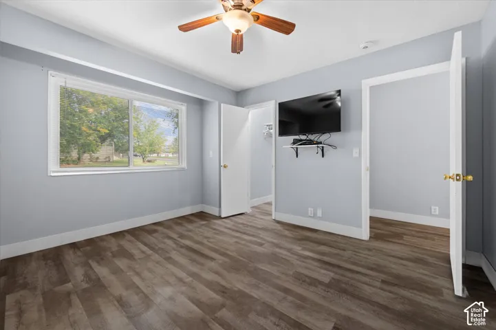 Room featuring wood-finish flooring, a ceiling fan with integrated lighting, and a large window