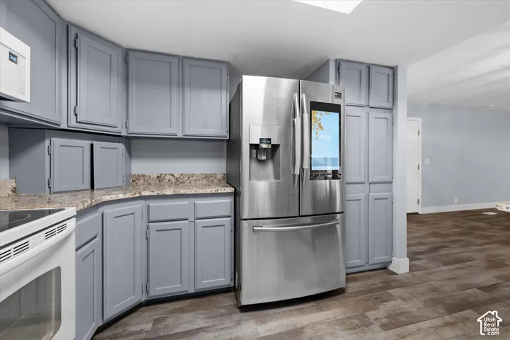 Kitchen featuring painted cabinetry, stone-surface countertops, wood-finish flooring, and a stainless steel smart refrigerator