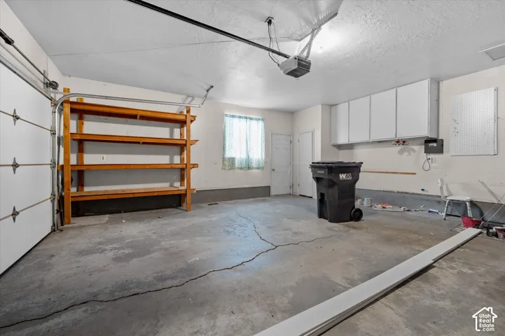 Garage space featuring a concrete floor, built-in wooden shelving, and overhead storage cabinetry