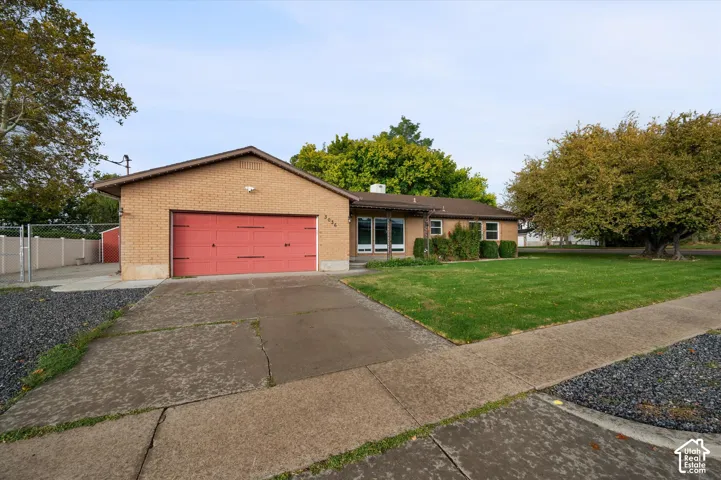 Single-story brick exterior featuring a multi-pane window configuration, an attached two-car garage, and a concrete driveway