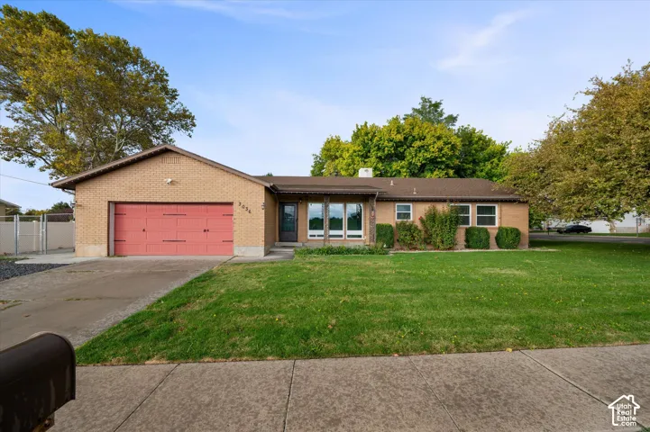 Single-story brick exterior featuring an attached two-car garage, multi-pane windows, and a concrete driveway