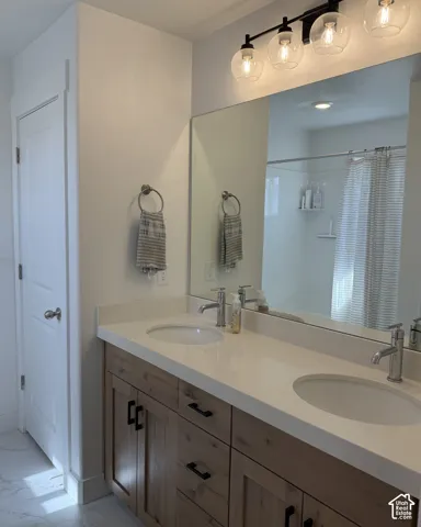 Dual vanity with light wood-finish cabinetry, white countertop, and integrated sinks