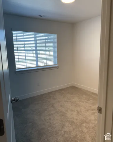 Recessed ceiling light, neutral-toned walls, window with horizontal blinds, and grey carpeting