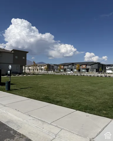 Expansive green space with manicured lawn, bordered by a concrete sidewalk