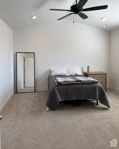 Vaulted ceiling with recessed lighting and a ceiling fan, light-toned carpeting