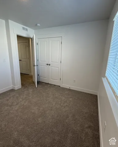 Plush carpet flooring, white walls, white trim, and a white interior door
