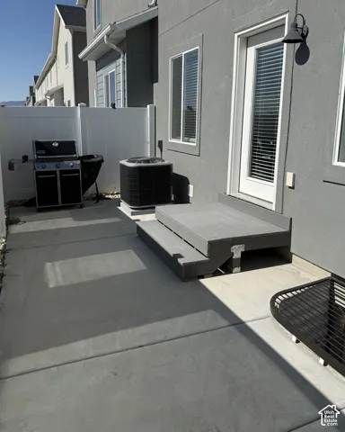 Concrete patio with a composite deck landing and a white privacy fence