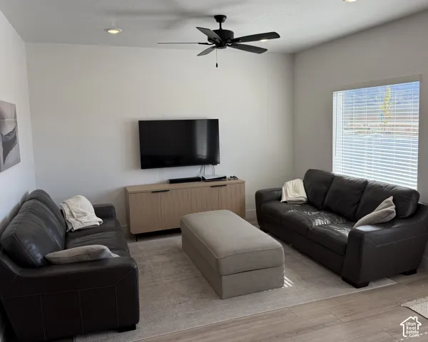 Recessed ceiling lighting, wood-finish flooring, ceiling fan, large window with blinds, entertainment console