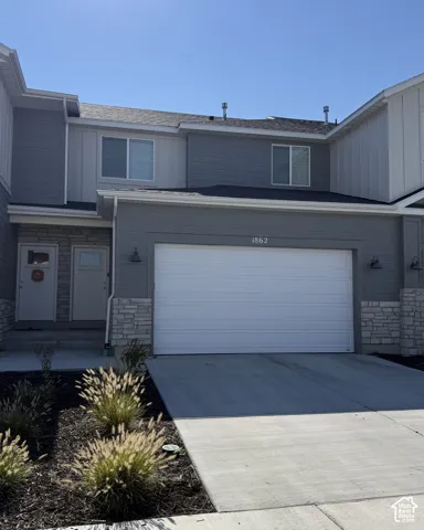 Two-story townhouse exterior featuring gray cement board and stone accents