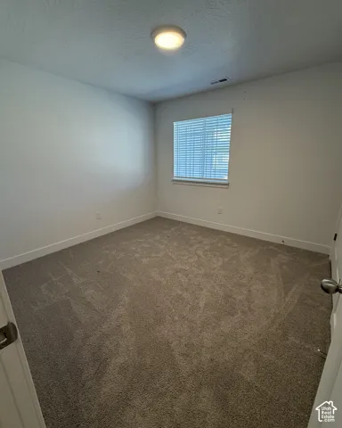 Neutral-toned carpeting, white walls, and a single window with blinds
