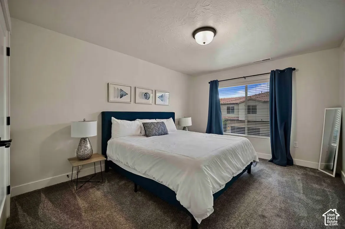 Neutral wall tones, overhead flush-mount lighting, dark-toned carpeting, white trim, and a window with horizontal blinds