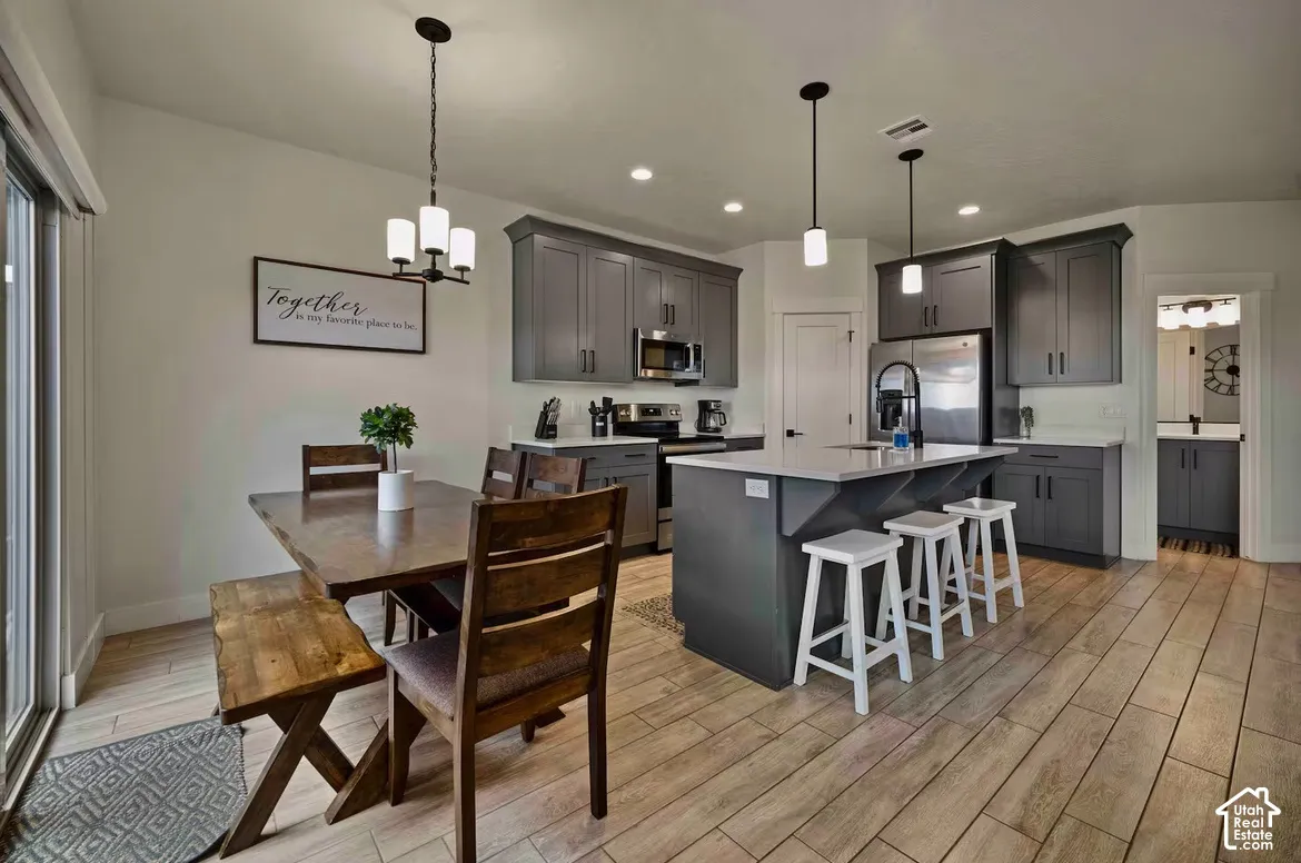 Kitchen with gray cabinetry, stainless steel appliances, and a central island with bar seating