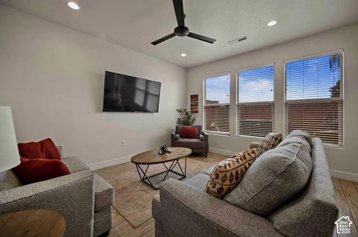 Recessed ceiling lighting, wood-finish flooring, a ceiling fan, and multiple windows with blinds