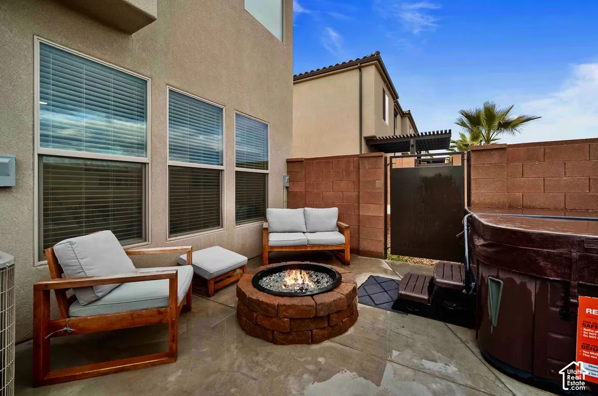 Paved patio area featuring a stone fire pit, block wall enclosure, and a spa