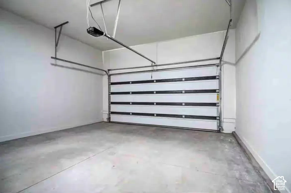 Spacious garage featuring a concrete floor, white walls, and an automatic garage door opener