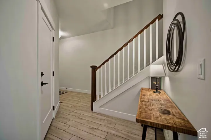 Wood-finish flooring, white walls, and a staircase with white spindles and a wood handrail
