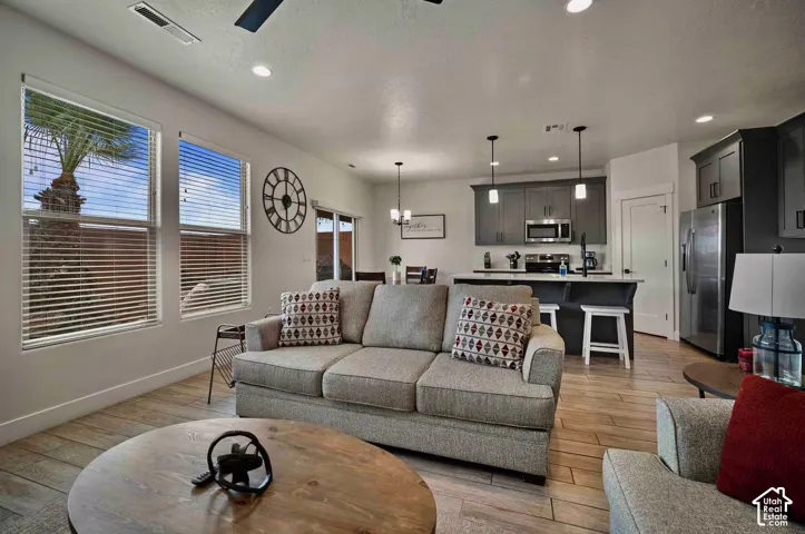 Open-concept living area with wood-finish flooring, recessed lighting, and a ceiling fan