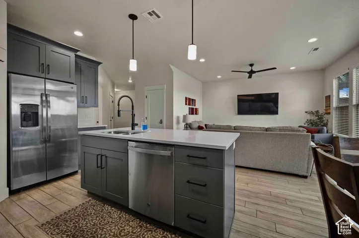 Kitchen island with white countertop, dark gray cabinetry, and stainless steel appliances