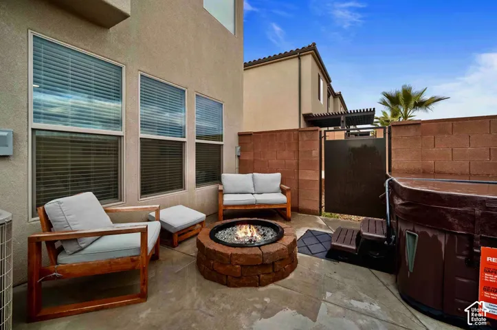 Paved patio area featuring a stone fire pit, block wall enclosure, and a spa
