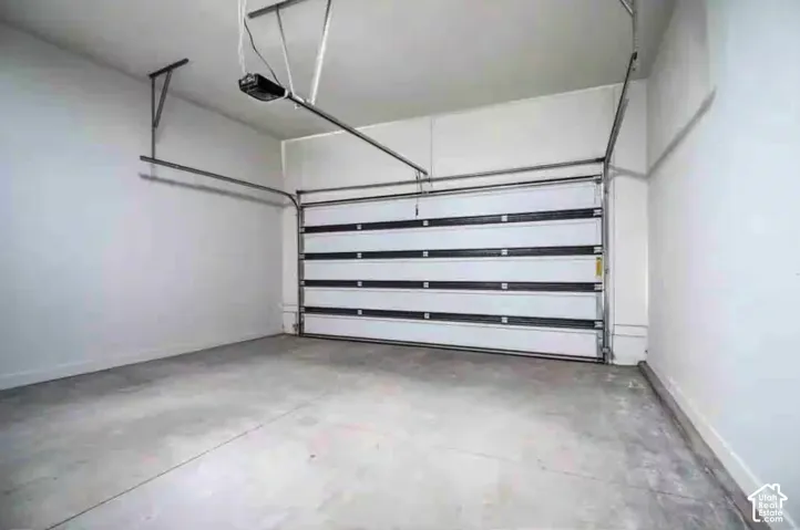 Spacious garage featuring a concrete floor, white walls, and an automatic garage door opener