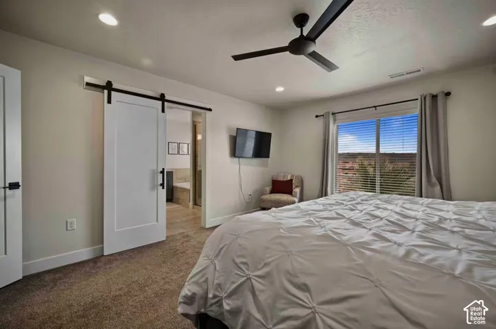 Recessed lighting, ceiling fan, carpet flooring, sliding barn door, and a large window with horizontal blinds