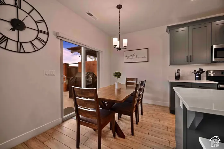 Kitchen and dining area featuring wood-finish flooring, dark grey cabinetry, white countertops, and stainless steel appliances