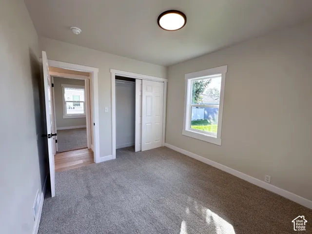 Carpeted room with a double-paned window, flush-mount ceiling light, and sliding closet doors