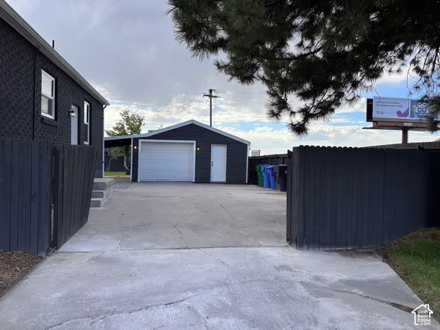 Concrete driveway leading to a detached garage with an overhead door, and a separate carport structure