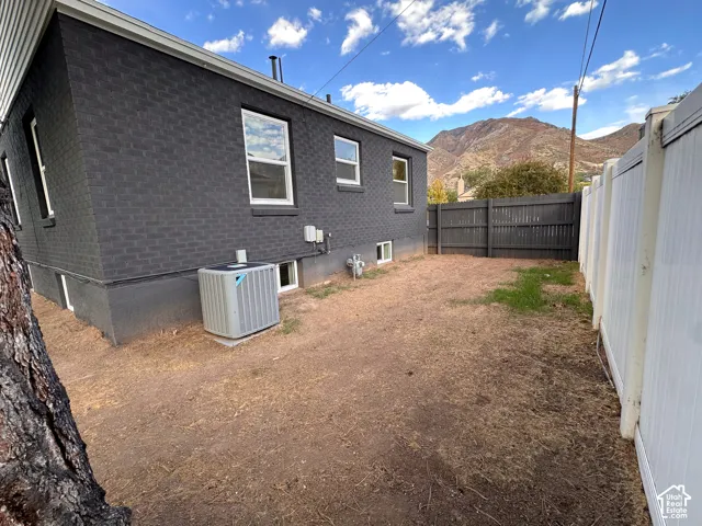Exterior featuring dark-toned masonry siding, a vinyl perimeter fence, and mountain scenery