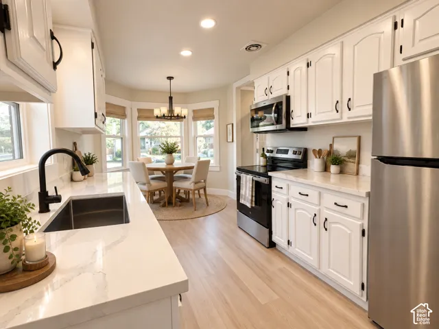 Kitchen featuring white shaker-style cabinetry, quartz countertops, stainless steel appliances, a matte black faucet with an undermount sink, and wood-finish flooring