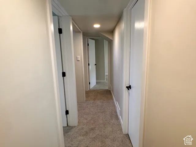 Hallway featuring neutral-toned carpeting, recessed lighting, and solid-core doors with matte black hardware