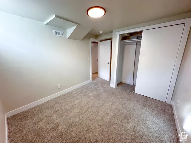 Plush carpeting, recessed ceiling light, white sliding closet doors, and light neutral wall finishes