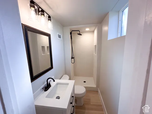 Modern bathroom featuring a white vanity with integrated sink, black-framed mirror, and a walk-in shower with a black shower system