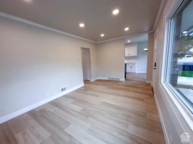 Recessed ceiling lighting, crown molding, wood-finish flooring, and white trim