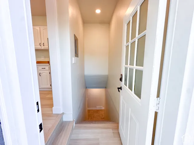 White paneled door with glass inserts, light wood-finish flooring, and recessed ceiling lighting