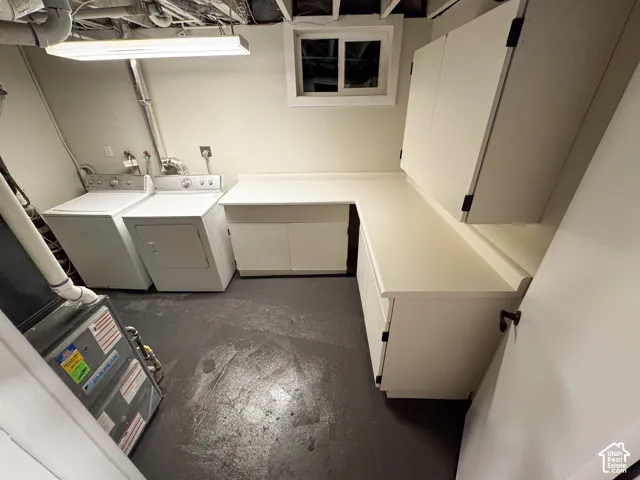Utility room featuring an L-shaped built-in workstation with solid surface countertops, extensive upper and lower cabinetry, and a slider window