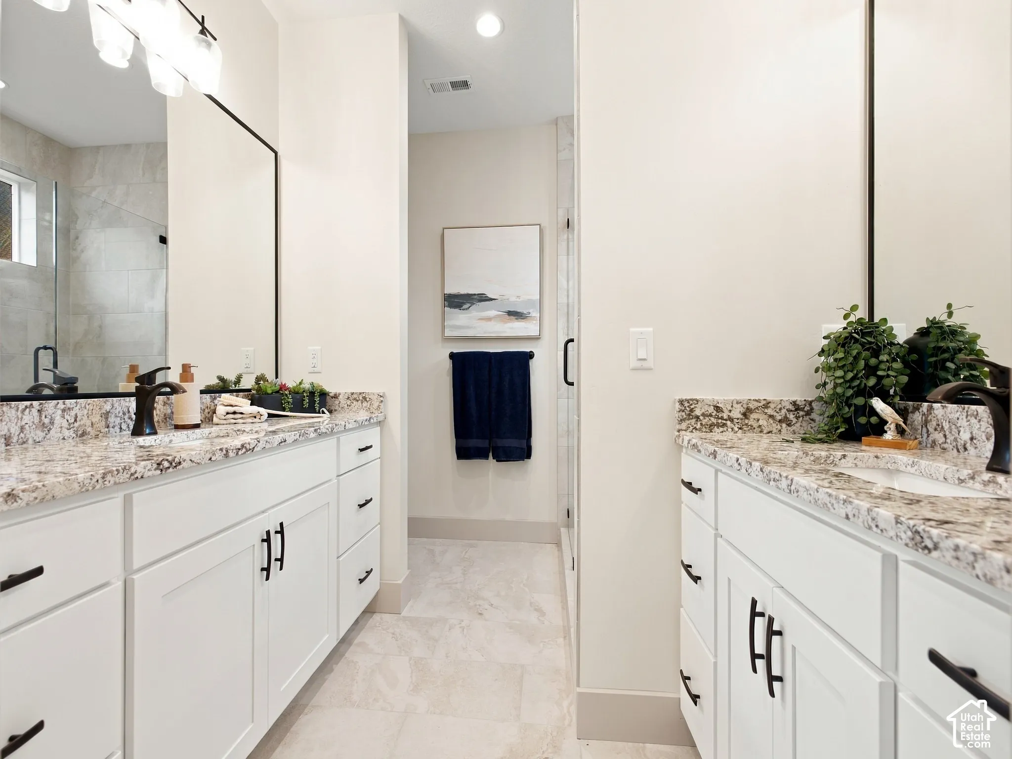 Dual vanities with stone countertops, white shaker cabinetry, and matte black hardware